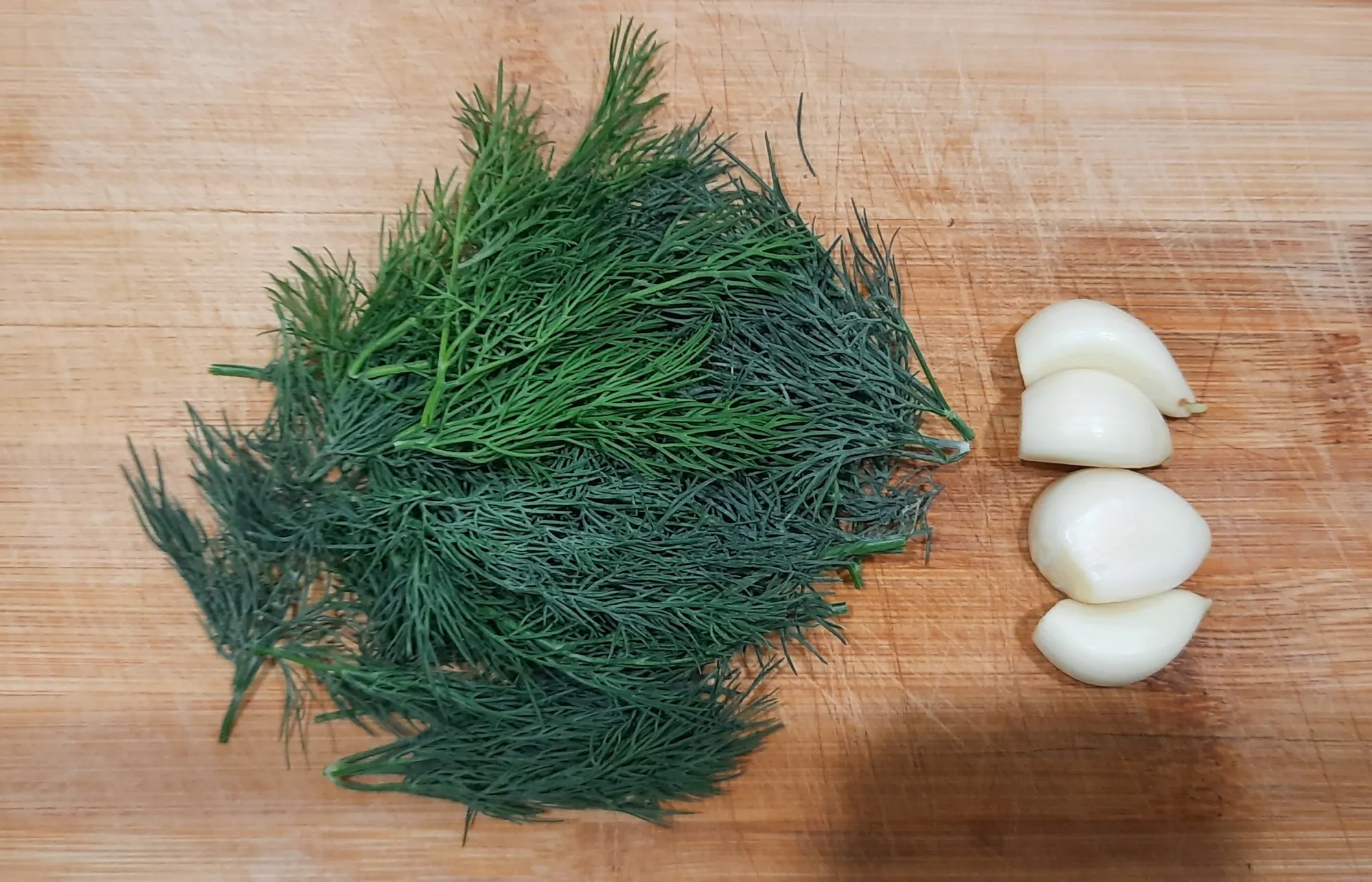 На 150-170 грамм сливочного масла нарезаем несколько веточек укропа и несколько зубчиков чеснока