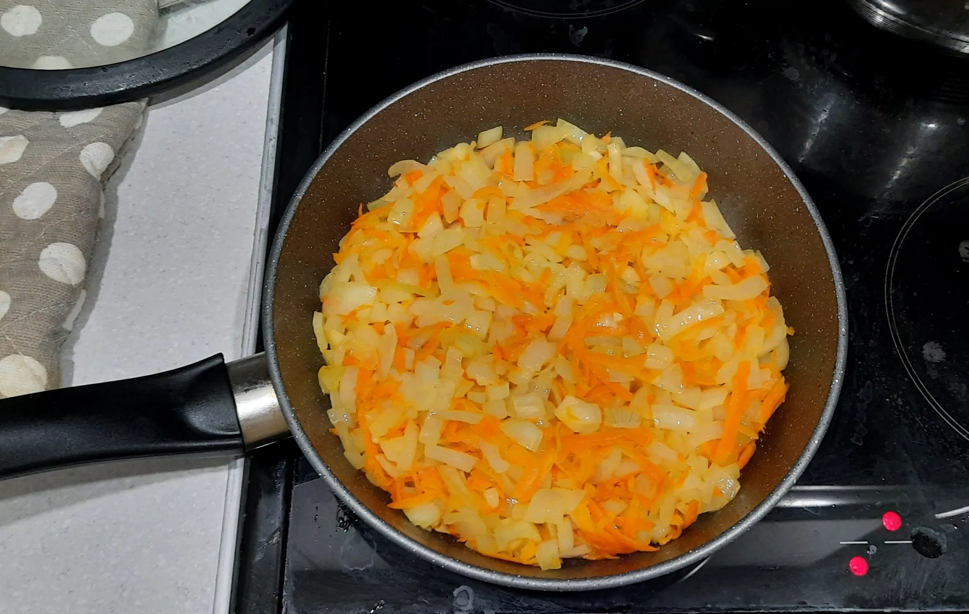 Через некоторое время к моркови добавляем лук. Продолжаем обжаривать всё вместе.
